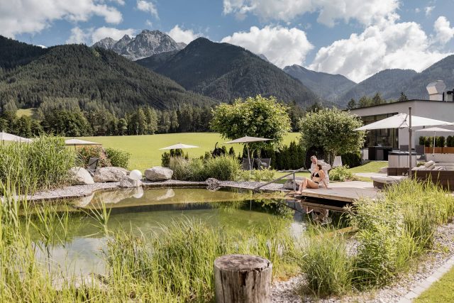 Frau entspannt am Naturpool mit Bergblick